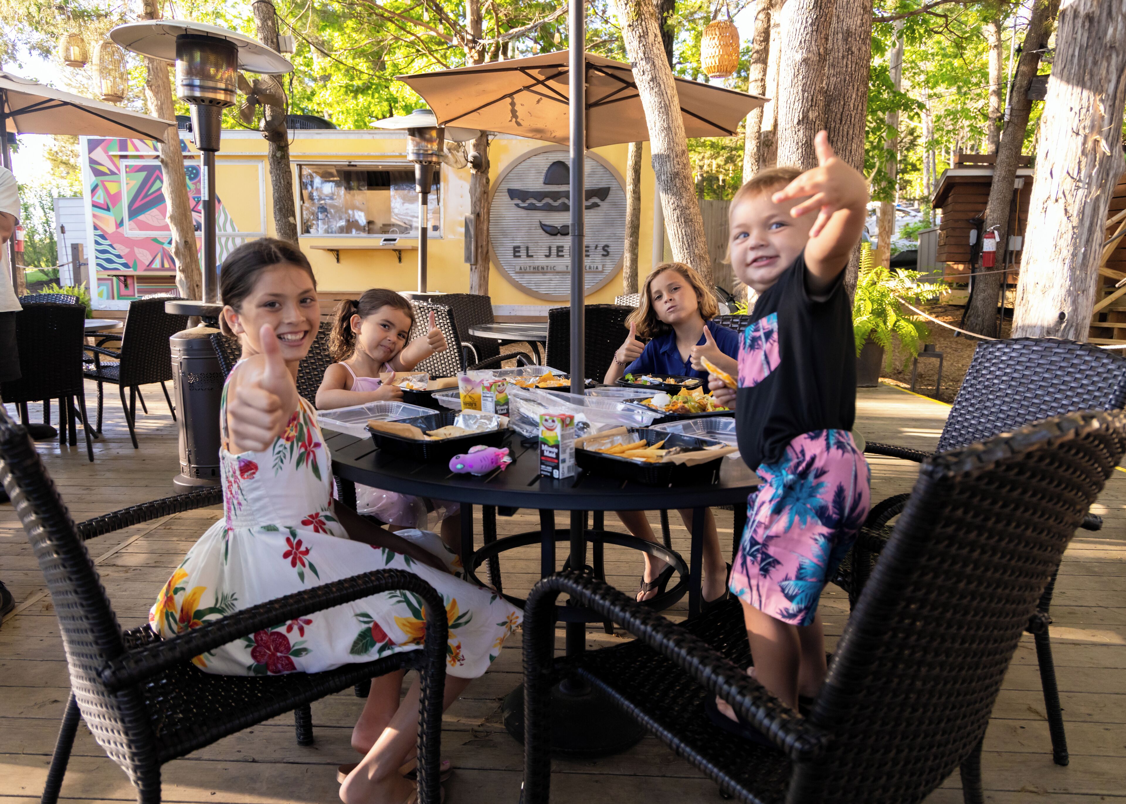 An outdoor dining area with wicker chairs, a table with food, and a mural in the background.