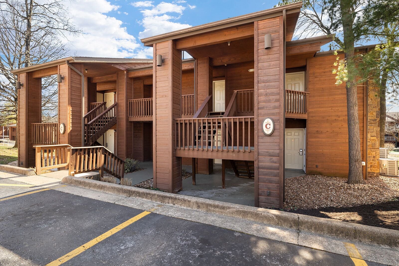 A wooden cabin-style building with a covered porch, a staircase, and a garage door.