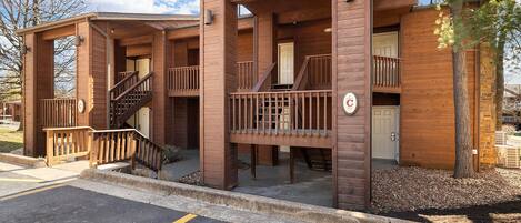A wooden cabin-style building with a covered porch, a staircase, and a garage door.