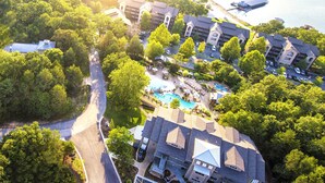 An aerial view of a resort with multiple buildings, a swimming pool, and a dock. - Still Waters Resort (Branson)