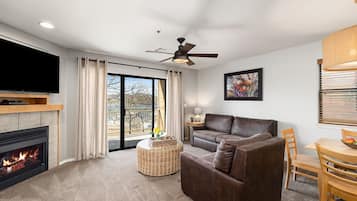 A living room with a fireplace, a sofa, a television, and a dining area with a table and chairs.