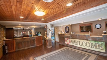 A reception area with a wooden ceiling, a welcome banner, a clock, and a reception desk.
