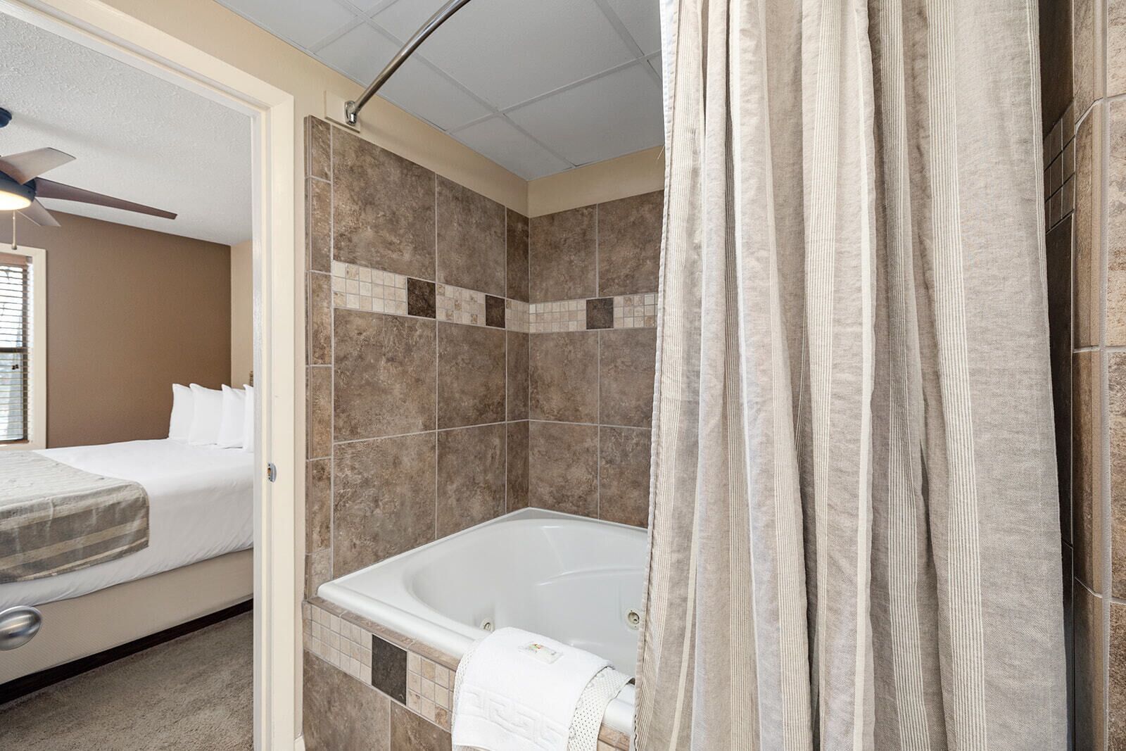 A hotel bathroom with a bathtub, shower curtain, and tiled walls.