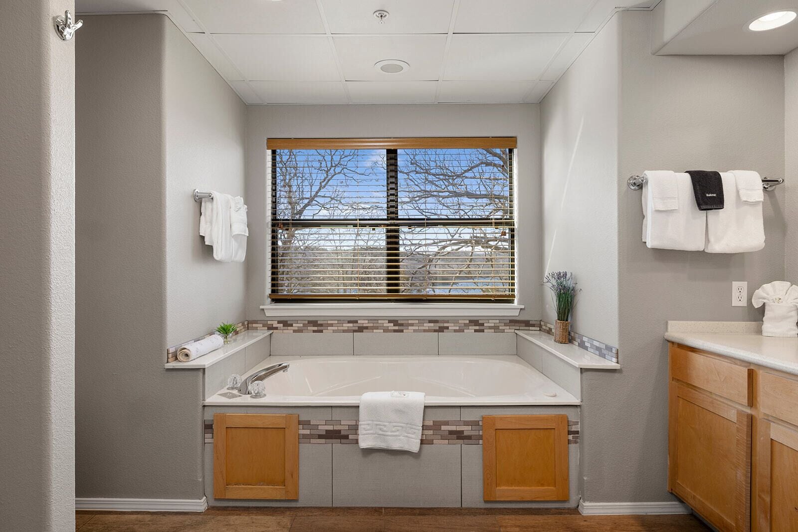 A modern bathroom with a freestanding bathtub, a window with blinds, and a towel rack.