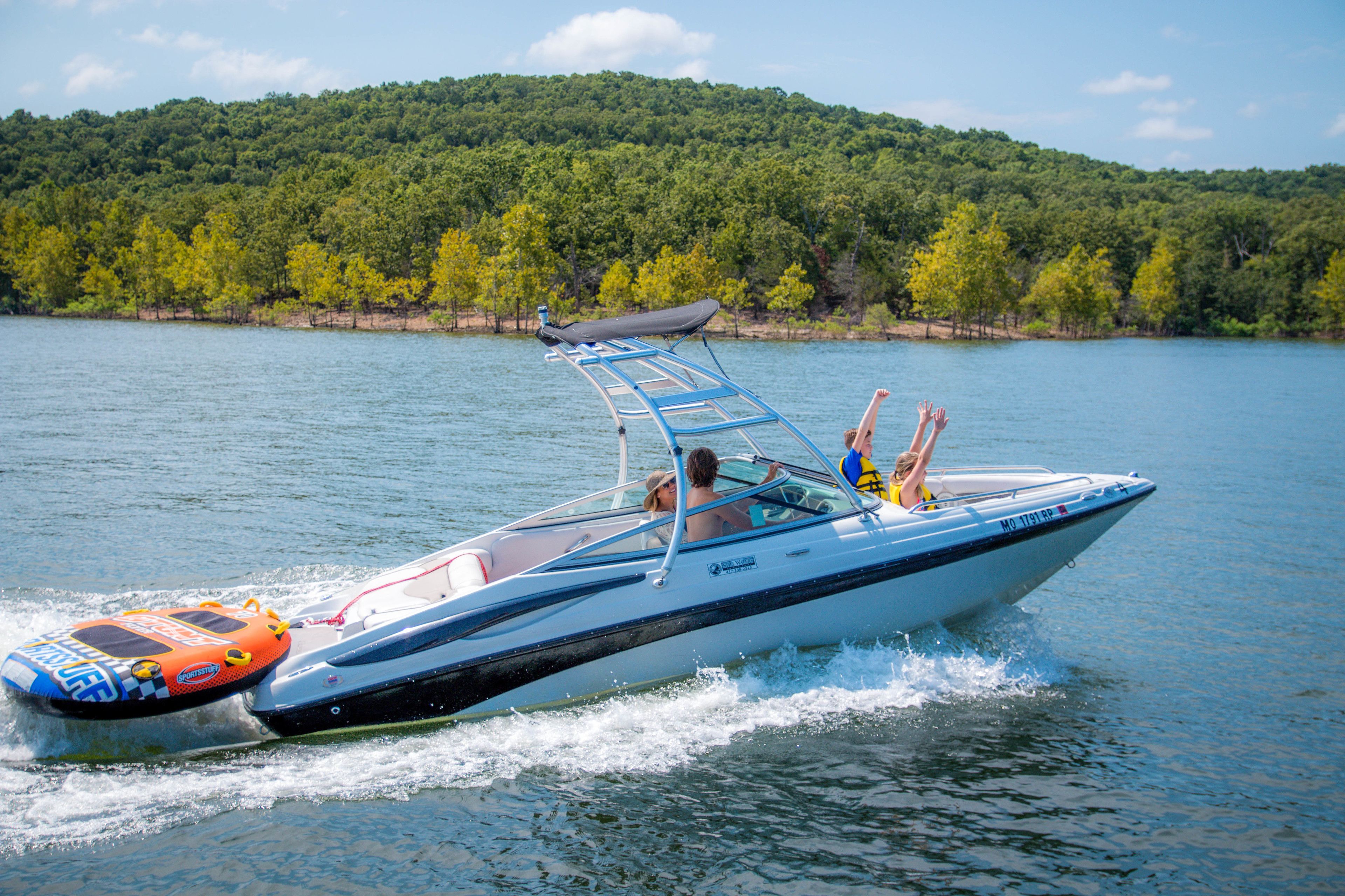 A speedboat on a lake with a forested shoreline in the background.