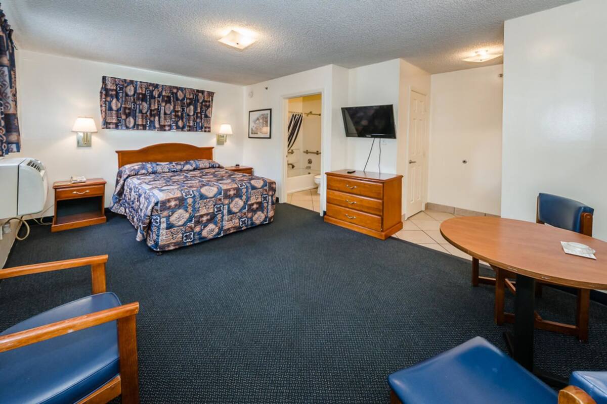 Une chambre d’hôtel comprenant un lit, un bureau, une chaise, une commode, un téléviseur et une table à manger.