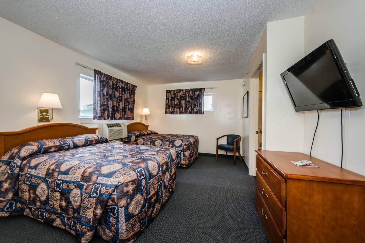 Une chambre d’hôtel avec deux lits, une télévision, une commode et une chaise.