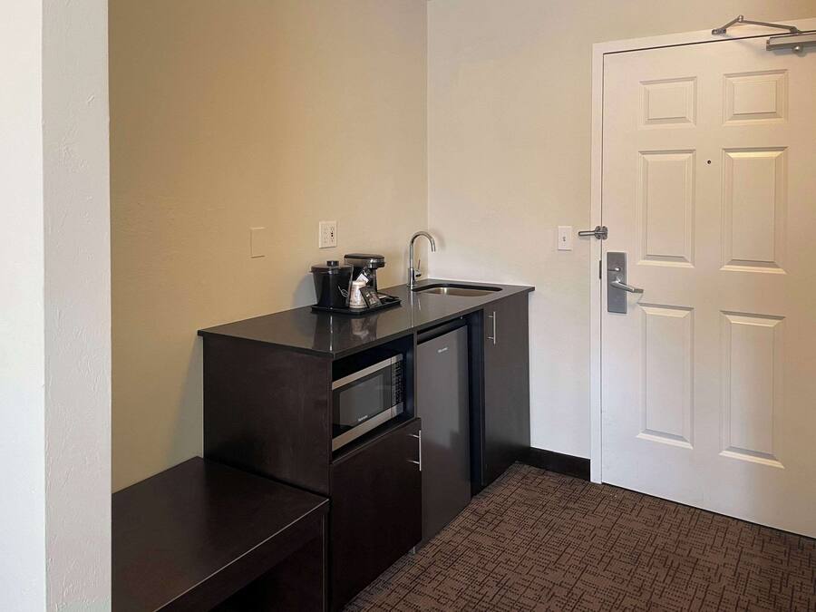 A compact kitchenette with a microwave, coffee maker, and sink.