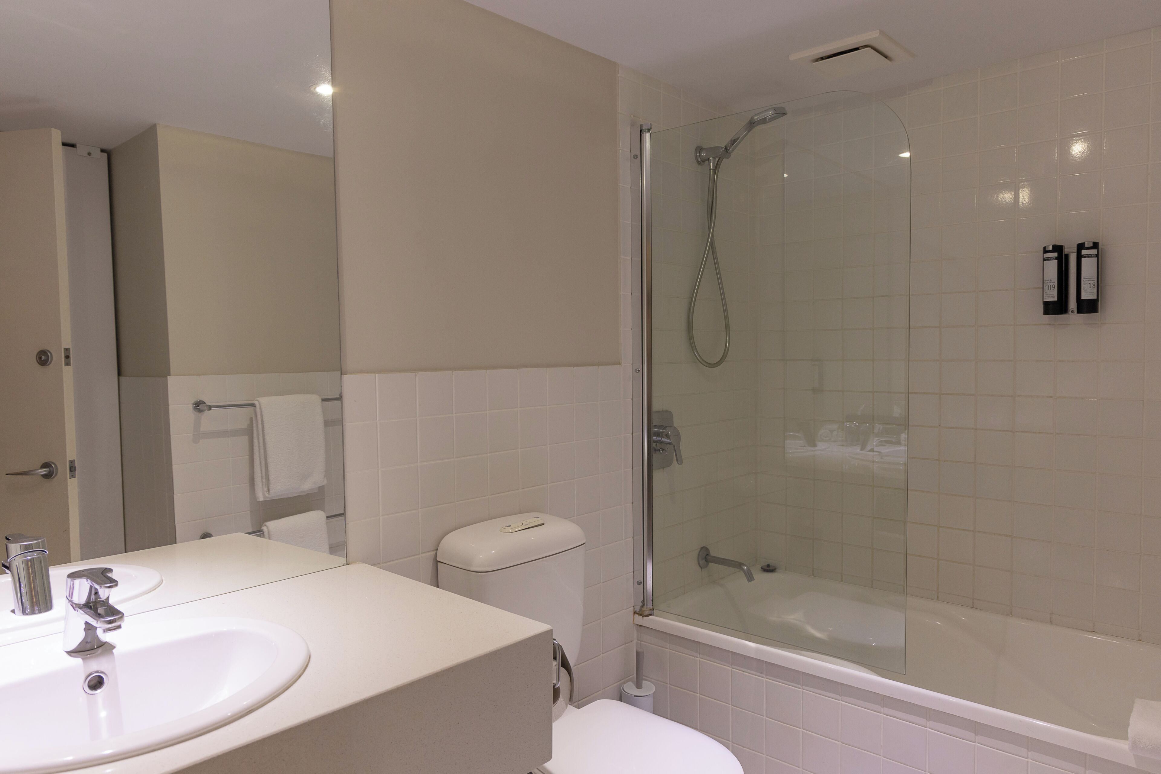 Een badkamer met een douchecabine van glas, een witte wastafel en een toilet.
