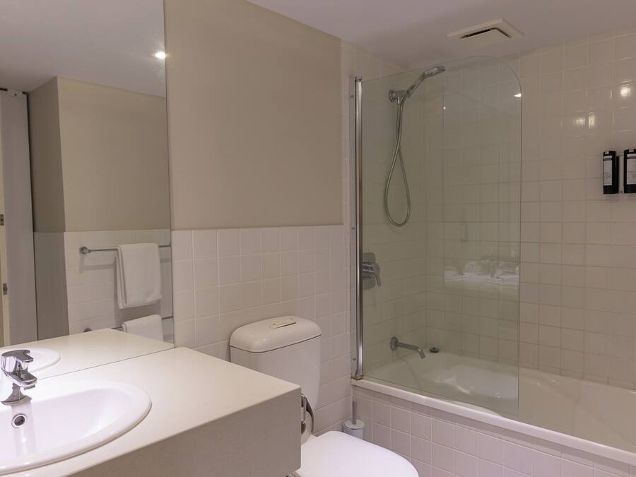 Een badkamer met een douchecabine van glas, een witte wastafel en een toilet.