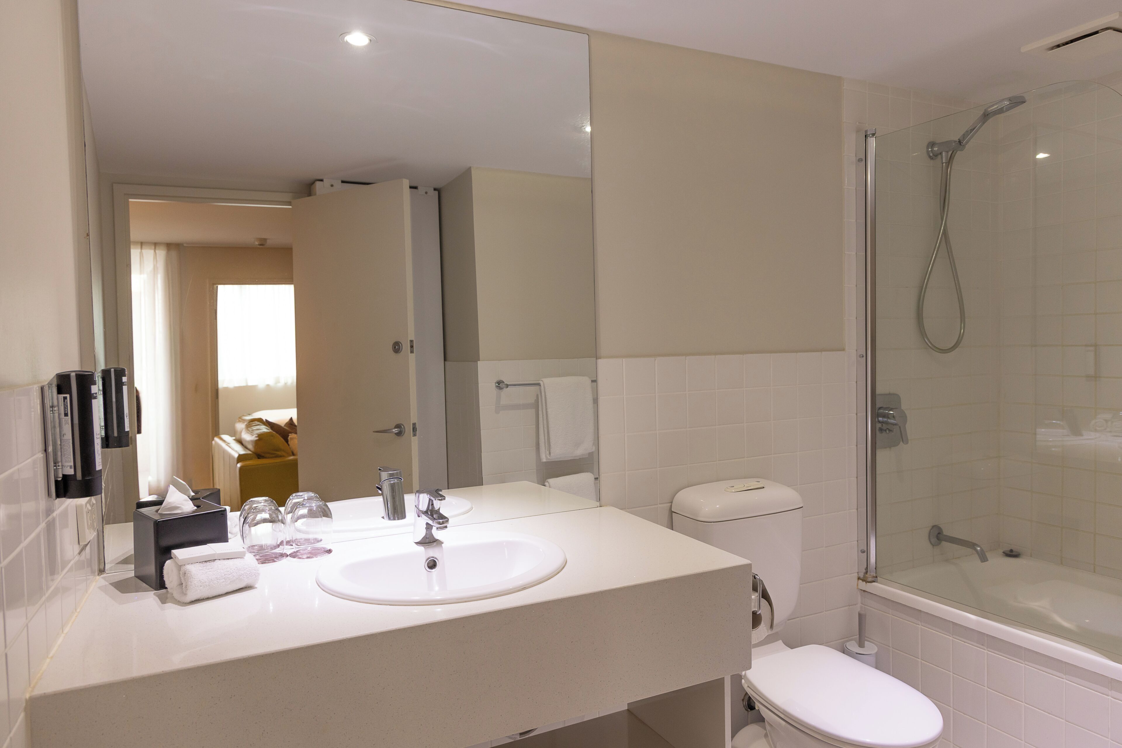 A bathroom with a white sink, mirror, toilet, and glass-enclosed shower.