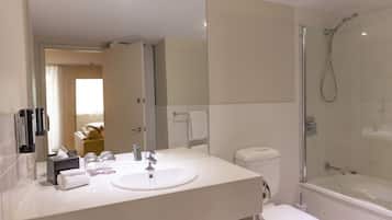 A bathroom with a white sink, mirror, toilet, and glass-enclosed shower.