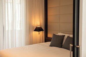 A hotel room with a bed, a nightstand, a lamp, and a window with curtains. - Point Hotel (Kangaroo Point)