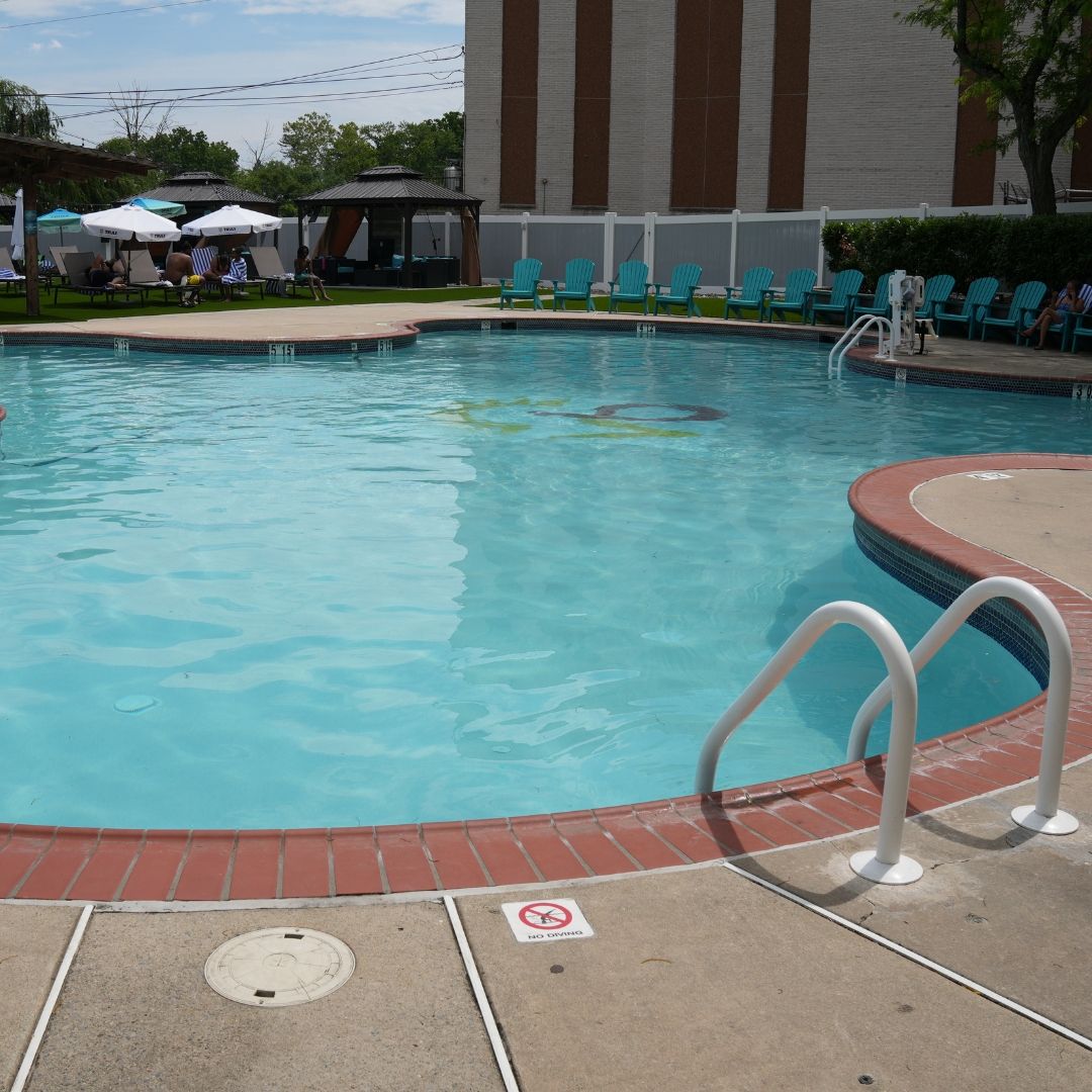 A swimming pool with a no diving sign, lounge chairs, and a building in the background.
