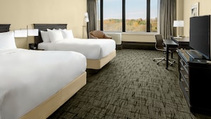 A hotel room with two beds, a desk, a chair, a TV, and a large window offering a view of the outdoors. - Valley Forge Casino Resort (King of Prussia)