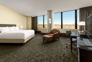 A hotel room with a large bed, a desk, a chair, and a view of the outdoors. - Valley Forge Casino Resort (King of Prussia)