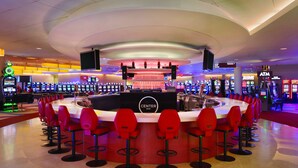 A bar area with a circular layout, multiple gaming machines, and red bar stools. - Valley Forge Casino Resort (King of Prussia)