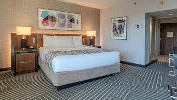 Una habitación de hotel con una cama grande, dos mesitas de noche con lámparas, un cabecero y una alfombra estampada.