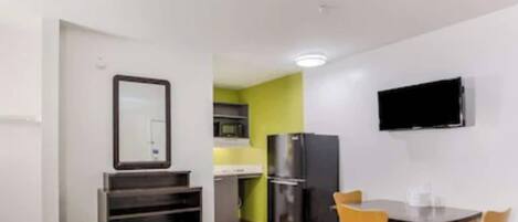 A compact kitchen with a refrigerator, microwave, and a dining area with a table and chairs.