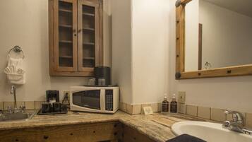 A kitchen with a microwave, coffee maker, and cabinets.