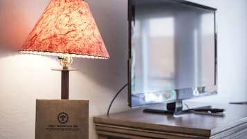 A lamp with a textured shade, a television on a wooden stand, and a sign with the logo "Table Mountain Inn".