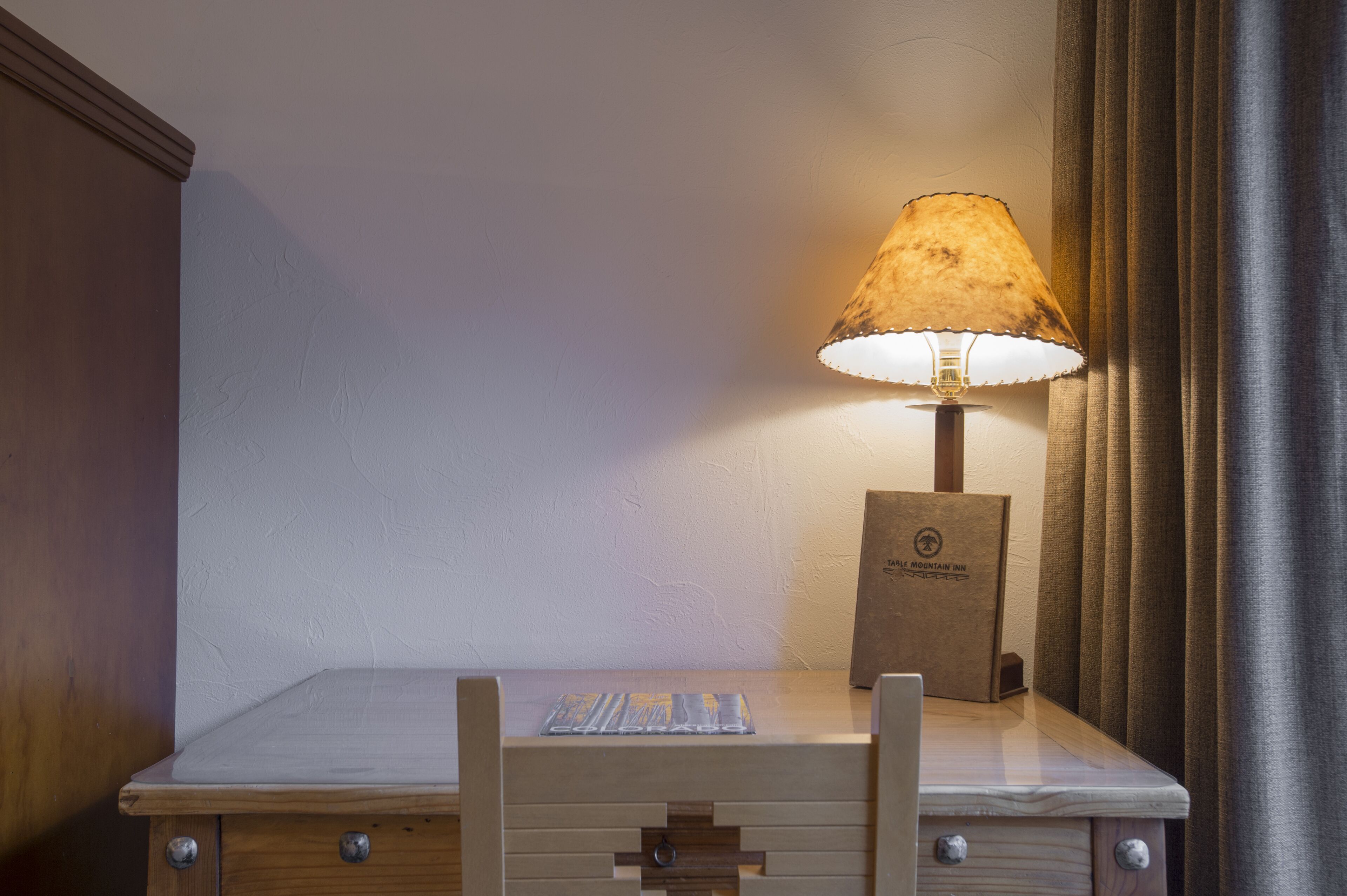 Una mesita de noche de madera con una lámpara, una tarjeta y una caja marrón.