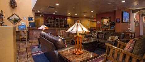 A lobby with leather sofas, a wooden coffee table, and a mounted deer head.