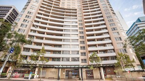 Un hotel de varios pisos con fachada curva, múltiples balcones y entrada a nivel de calle con un cartel que dice 'Mantra Chatswood'.