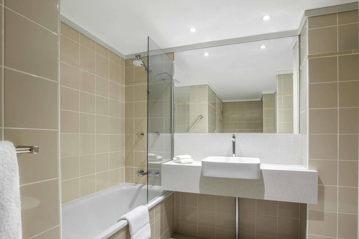 A modern bathroom with a glass shower enclosure, a bathtub, and a white sink.