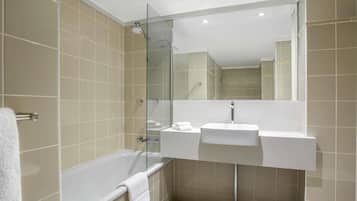 A modern bathroom with a glass shower enclosure, a bathtub, and a white sink.