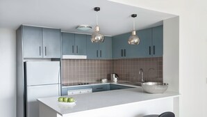 Una cocina moderna con armarios grises, una isla blanca, electrodomésticos de acero inoxidable e iluminación colgante.