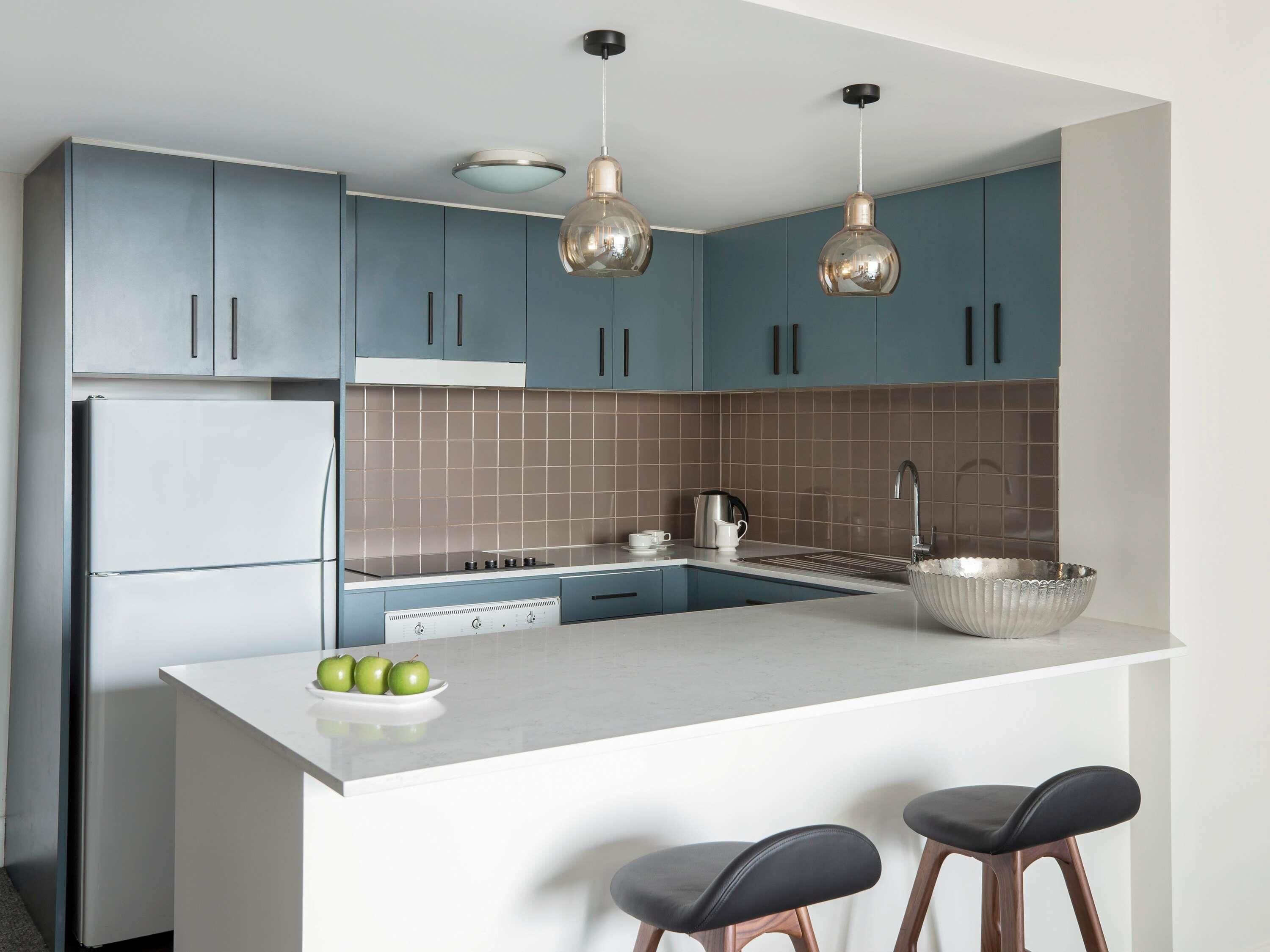 Una cocina moderna con una isla central, electrodomésticos de acero inoxidable y armarios azules.