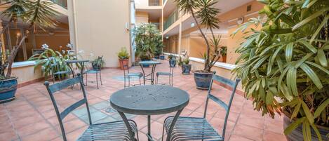 Une cour avec des sièges en plein air, des plantes en pot et un sol carrelé.