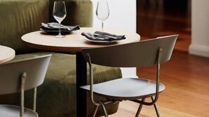 A dining area with a round table, a green upholstered chair, and a modern chandelier.