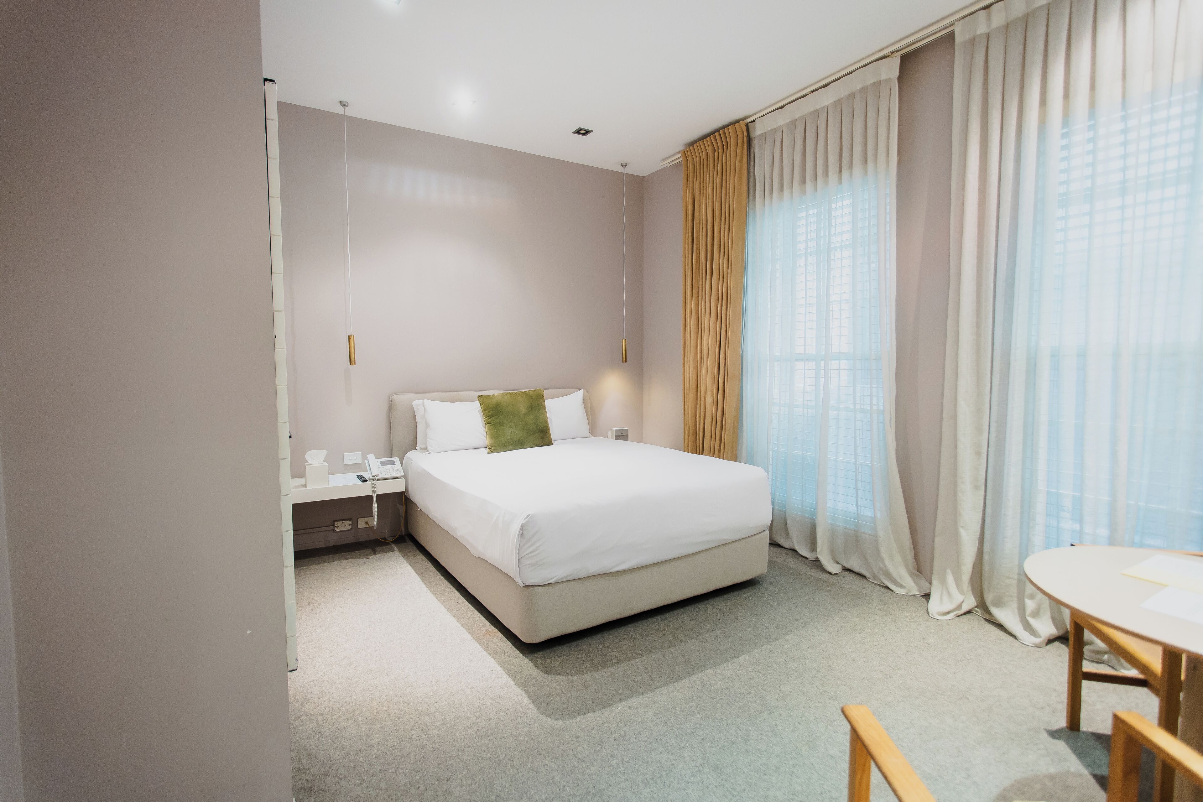 Une chambre d’hôtel avec un lit, une table de chevet, une lampe et une petite table avec des chaises.