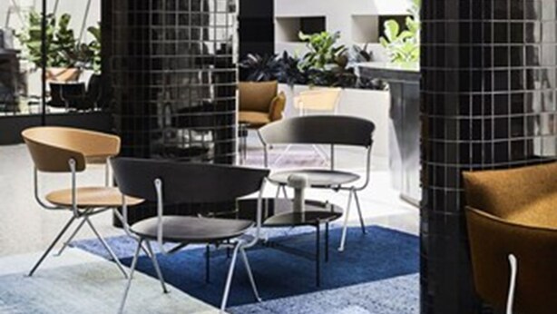 A modern interior with a mix of seating arrangements, including chairs and a table, and a staircase with a metal railing. - The Prince (St Kilda)