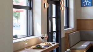 A dining area with a wooden table, two plates of food, and two glasses of wine. - The Prince (St Kilda)