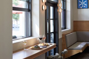 A dining area with a wooden table, two plates of food, and two glasses of wine.