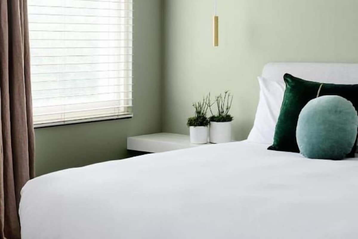 A modern bedroom with a bed, bedside tables, and a window with curtains.