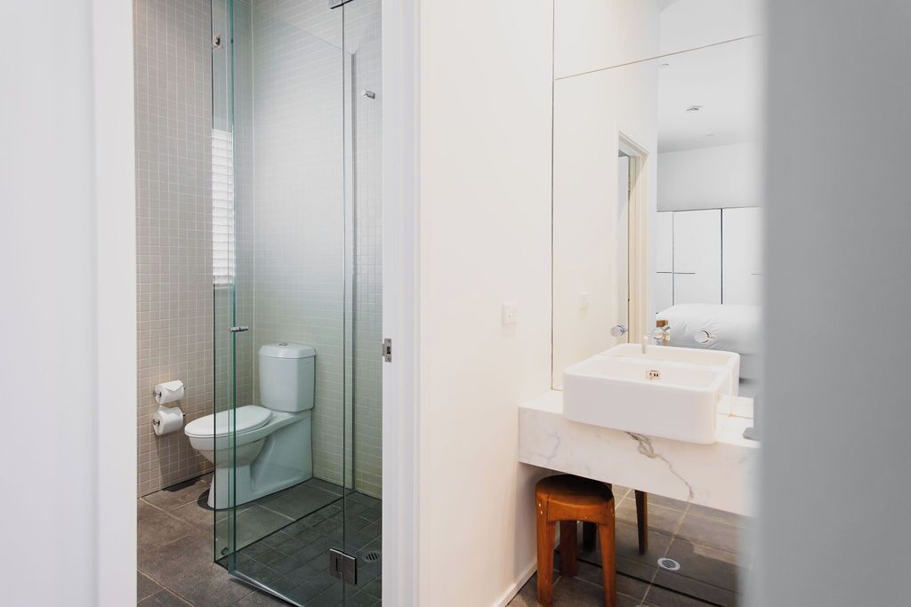 A modern bathroom with a glass-enclosed shower, a white toilet, and a marble sink.