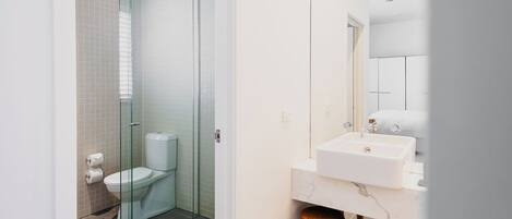 A modern bathroom with a glass-enclosed shower, a white toilet, and a marble sink.