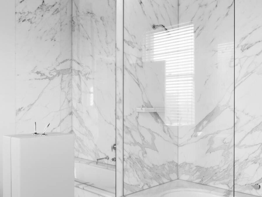 A modern bathroom with a glass-enclosed shower, a white sink, and a toilet.