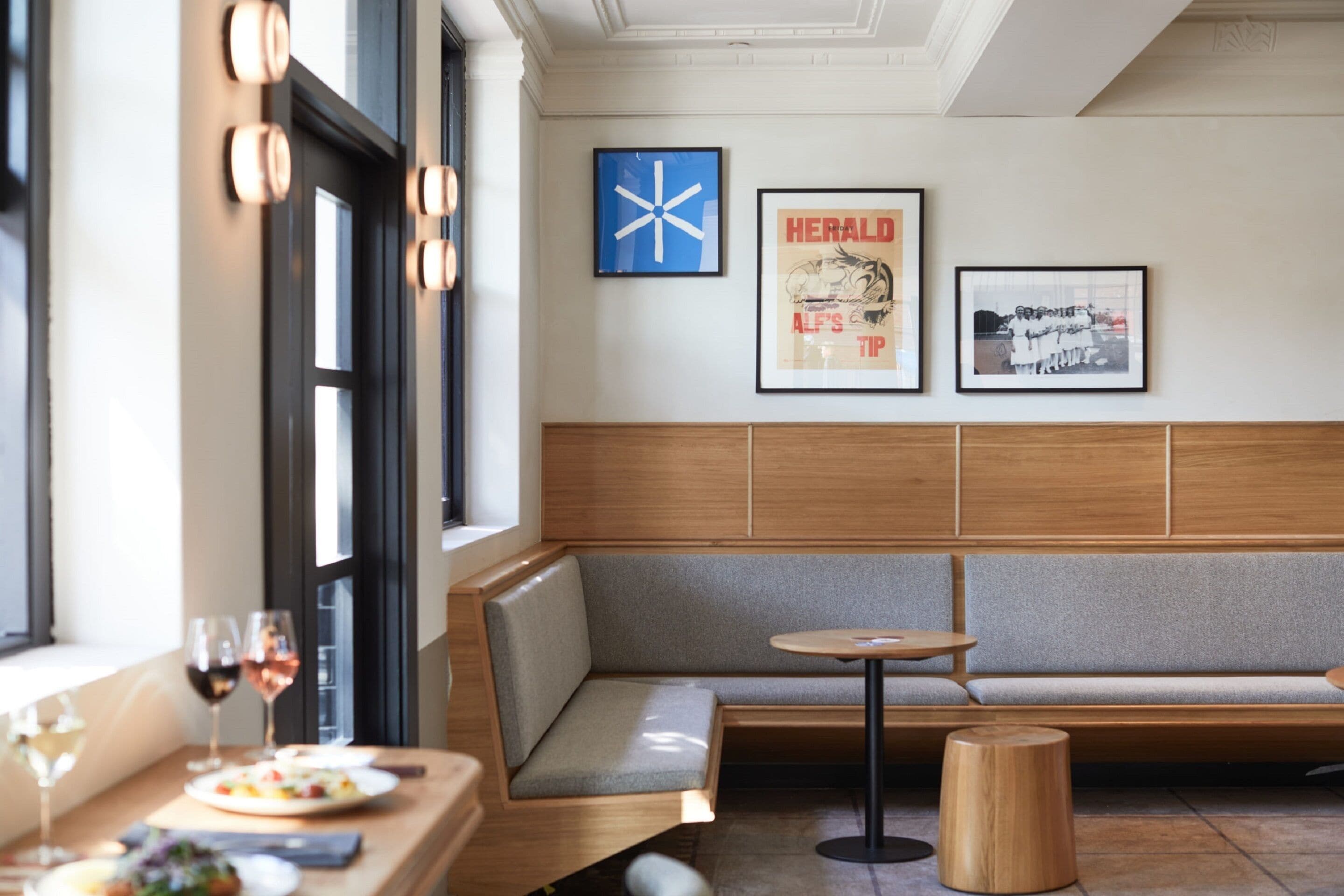 Ein modernes Interieur mit einer hölzernen Bank, einem runden Tisch und gerahmten Bildern an der Wand.