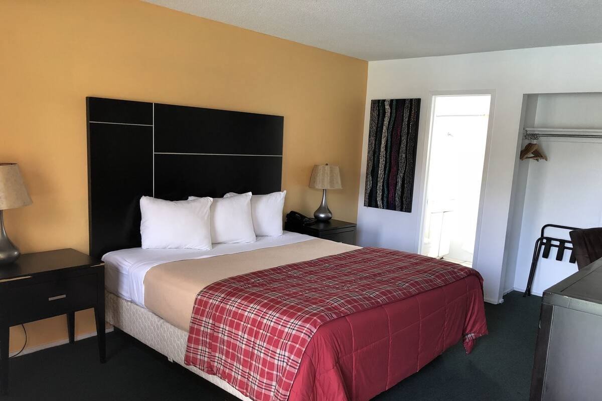 Una habitación de hotel con cama, mesita de noche, escritorio, silla y ventana.