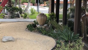 A landscaped garden area with a large planter, various shrubs, and a curved pathway. - Desert Lodge (Palm Springs)