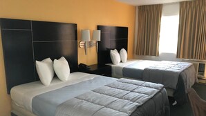 A hotel room with two beds, a large window with curtains, and a wall-mounted lamp. - Desert Lodge (Palm Springs)