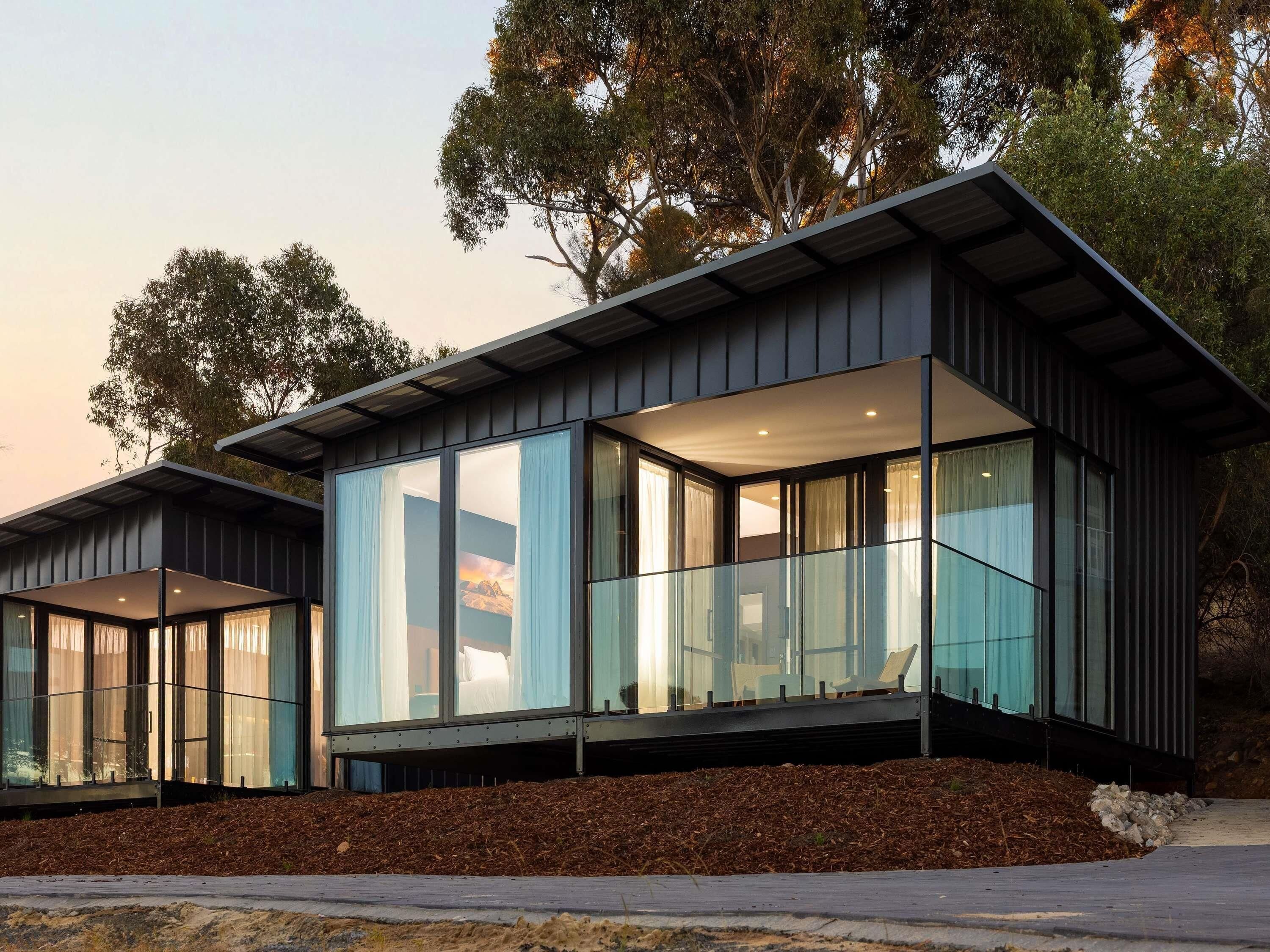 A modern two-story house with large glass windows and a flat roof.