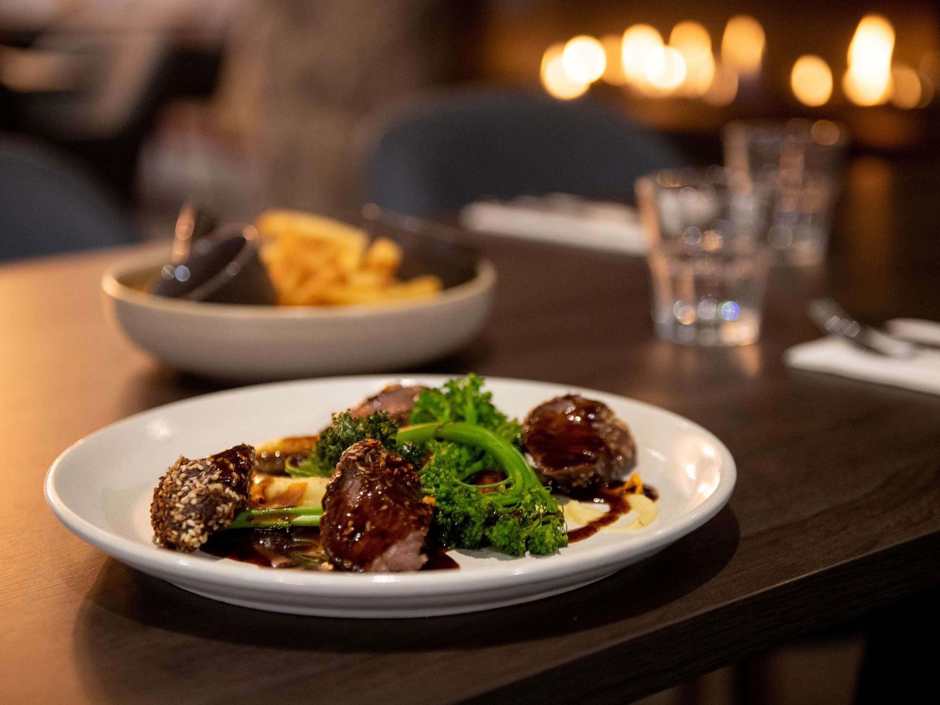A plate of food with meatballs and broccoli on a table.