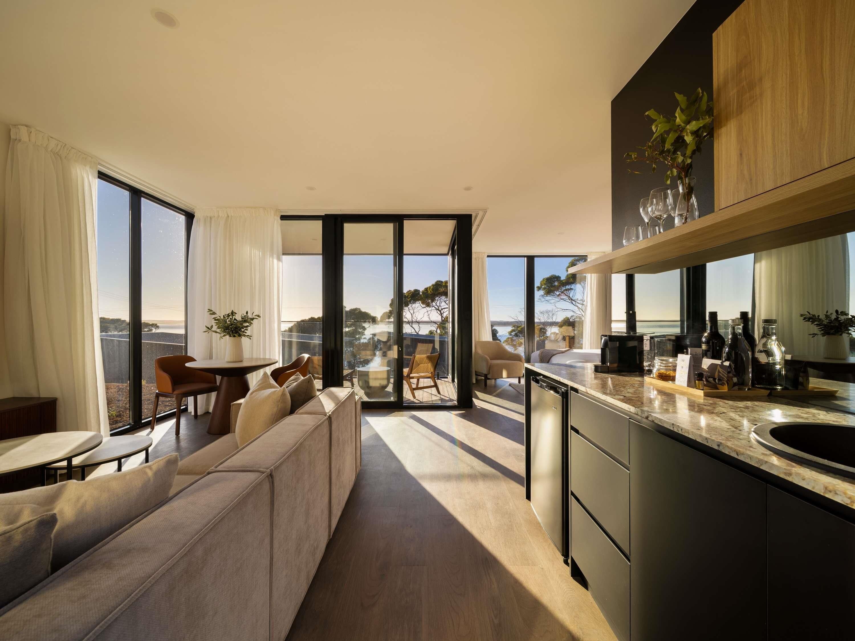 A modern kitchen with a large island, a dining area with a sofa, and a view of the outdoors.