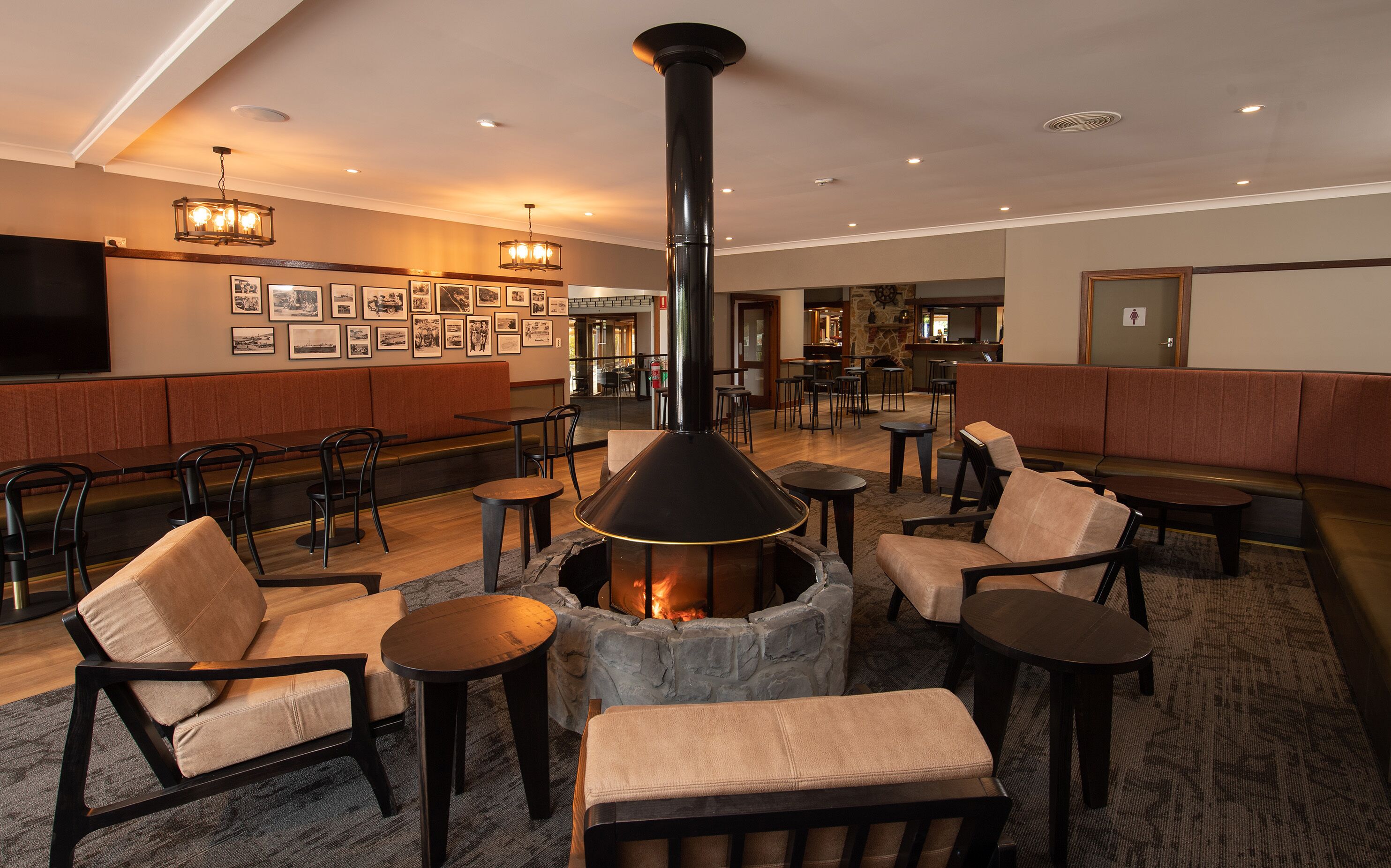 A cozy lounge area with a stone fireplace, comfortable seating, and a bar area in the background.